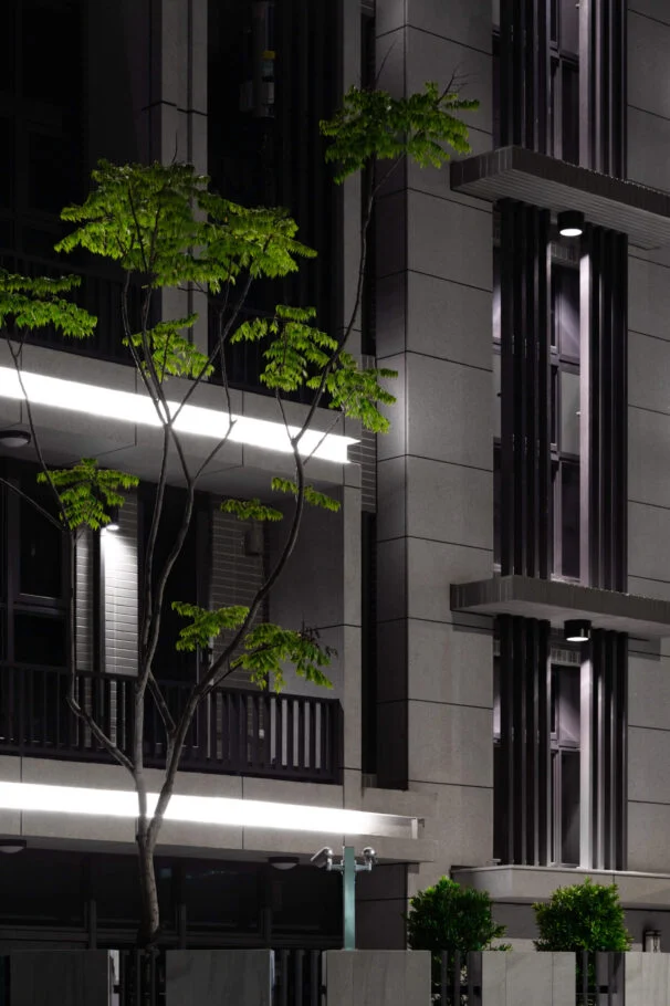 東其建設・文山晶硯｜夜間立面窗框、燈帶與前方植栽