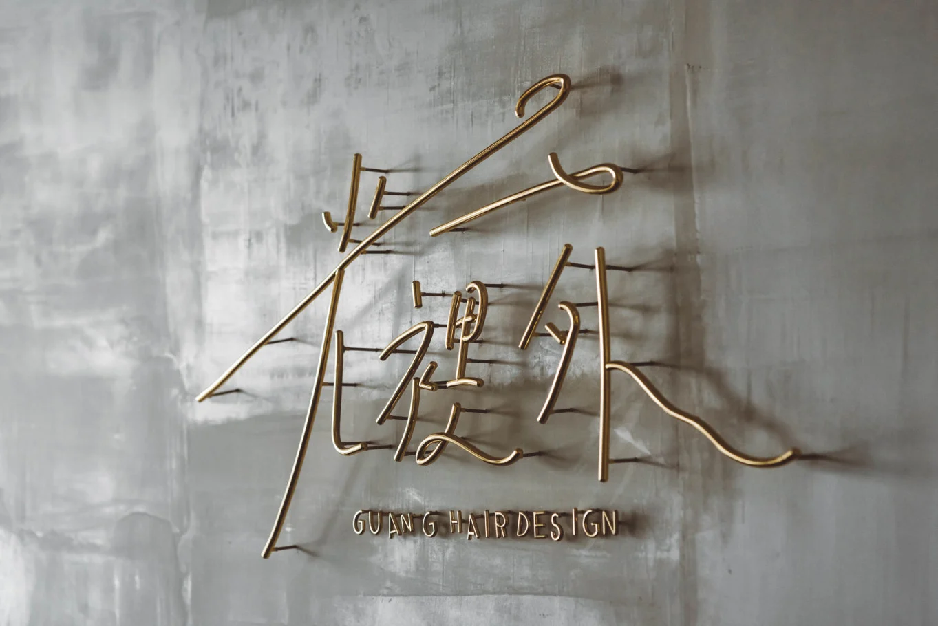 川彡志作・光裡外|灰色紋理牆上的金色品牌字樣